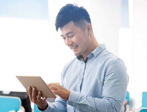 Un hombre sonríe mirando a una tablet