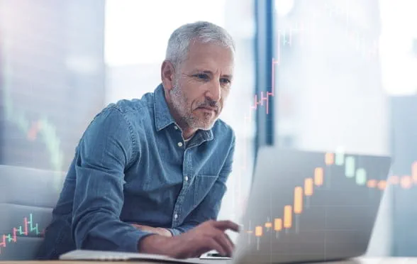 Hombre con barba mirando el mercado de criptomonedas en una laptop